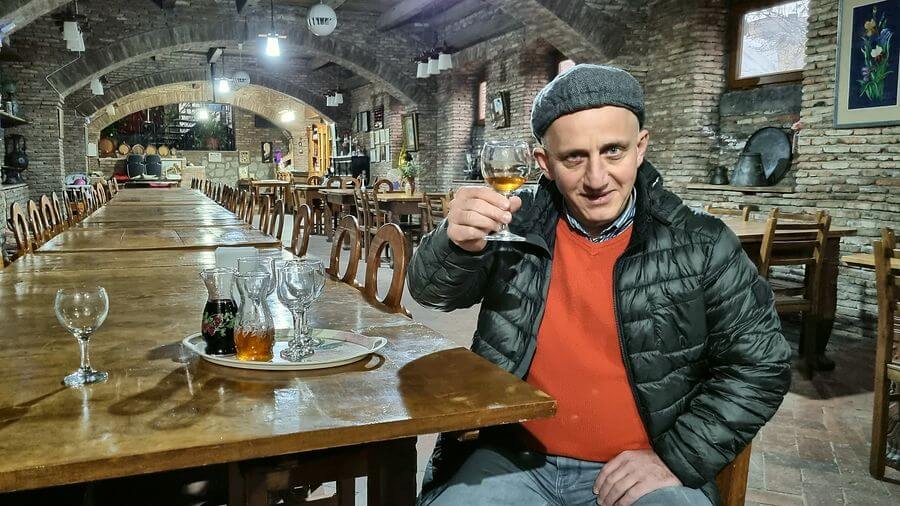 Gründer von OriGeo erhebt in einem Gewölbekeller ein Glas Wein, vor ihm eine lange Holztafel mit Karaffen